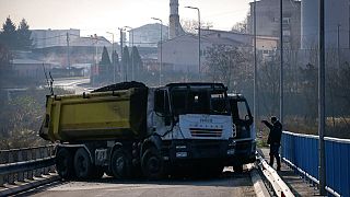 n hombre toma fotos de un camión quemado, parte de una barricada en el puente cerca de la parte norte dominada por los serbios de la ciudad étnicamente dividida de Mitrovica