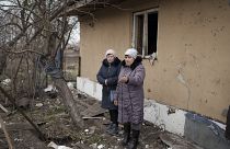 Local residents stand among debris after residential houses were damaged following a Russian missile attack in Kyiv.