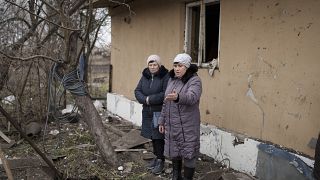 Local residents stand among debris after residential houses were damaged following a Russian missile attack in Kyiv.