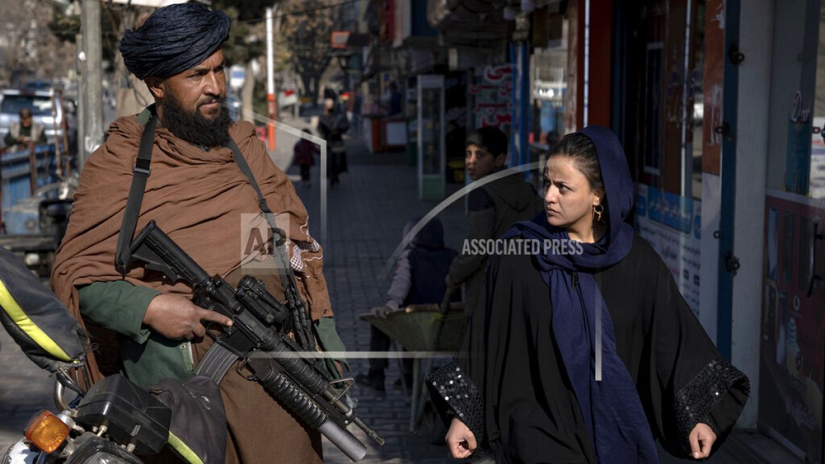 Un talebano controlla la strada mentre una donna passa a Kabul, in Afghanistan, il 26 dicembre 2022.