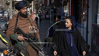Un talebano controlla la strada mentre una donna passa a Kabul, in Afghanistan, il 26 dicembre 2022.