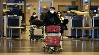 Passagiere aus China verlassen an einem römischen Flughafen den Testbereich.