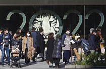 أشخاص يرتدون كمامات للحماية من انتشار فيروس كورونا يمشون أمام زينة العام الجديد في طوكيو، 30 ديسمبر 2021.