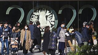 أشخاص يرتدون كمامات للحماية من انتشار فيروس كورونا يمشون أمام زينة العام الجديد في طوكيو، 30 ديسمبر 2021.