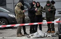 Police experts examine remains of a downed missile which fell on a vehicle parked at a multi storey residential building in Kyiv on December 29, 2022