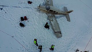 Rescuers digging through snow to free the wings of the plane. 
