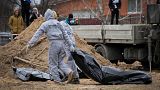 Men wearing protective gear exhume the bodies of civilians killed during the Russian occupation in Bucha, on the outskirts of Kyiv, Ukraine, Wednesday, April 13, 2022. 