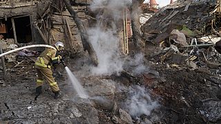 Firefighters extinguish a fire next to houses destroyed during a Russian attack in Kyiv, Ukraine, Saturday, Dec. 31, 2022. (AP Photo/Roman Hrytsyna)
