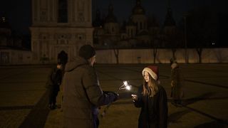 Una niña enciende una bengala en la Plaza de Sofía antes del toque de queda en la víspera de Año Nuevo en Kiev, Ucrania, el sábado 31 de diciembre de 2022.