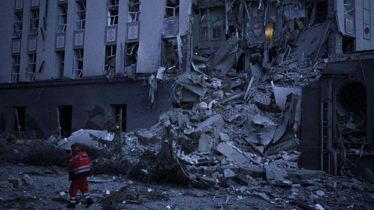 An emergency worker walks in front of a damaged hotel following a Russian attack in Kyiv, Ukraine, Saturday, Dec. 31, 2022. 