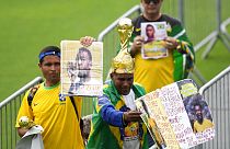 Fans hold up photos of the late Brazilian soccer great Pele as they line up at Vila Belmiro stadium where his body lies in state, to pay their last respects in Santos, Brazil,
