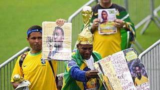 Fans hold up photos of the late Brazilian soccer great Pele as they line up at Vila Belmiro stadium where his body lies in state, to pay their last respects in Santos, Brazil,