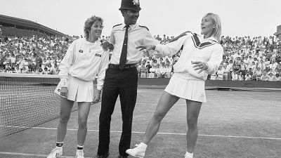 FILE - Chris Evert, left, and Martina Navratilova joke with police officer Les Bowie on Number Two Court at Wimbledon in London on July 4, 1985
