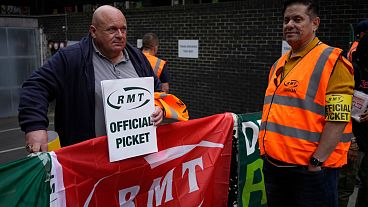 FILE: Workers and members of the RMT (The National Union of Rail, Maritime and Transport Workers) union stand on a picket line outside Euston train station, June 2022
