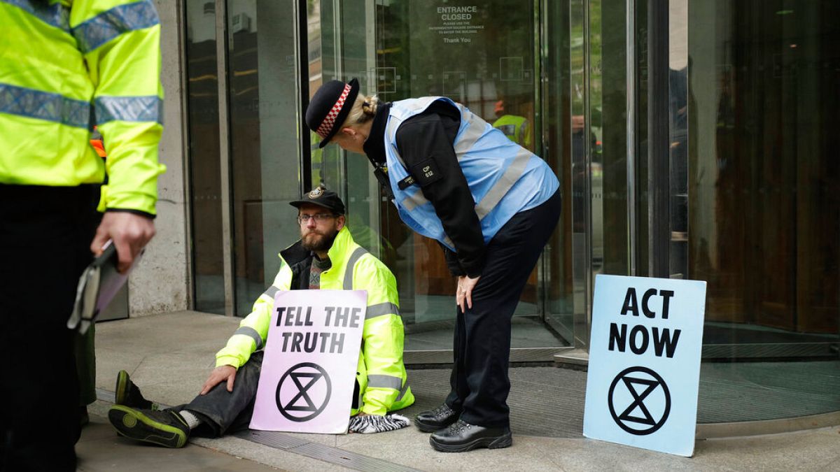 Un manifestant d'Extinction Rebellion avec sa main collée à l'exterieur de la Bourse de Londres. 25 avril 2019