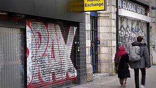 Pedestrians pass a closed down money exchange shop on Oxford Street in London, Friday, Nov. 11, 2022. 