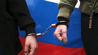 Two women wear a handcuff and a Russian flag as they attend a protest against the jailing of the Russian opposition leader Alexei Navalny in Berlin, Germany, April, 2021.
