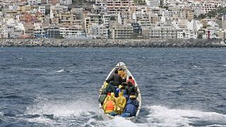 مهاجرون أفارقة في سفينة صيد خشبية مفتوحة عند اقترابهم من ميناء لوس كريستيانوس بإسبانيا.