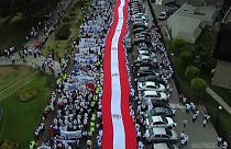 Cientos de personas llevan una bandera peruana en la manifestación por la paz en Lima este martes.