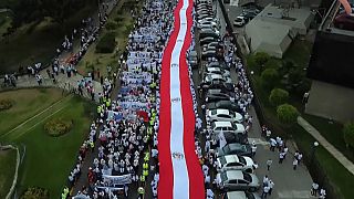 Cientos de personas llevan una bandera peruana en la manifestación por la paz en Lima este martes. 