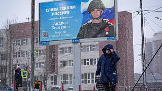 A woman walks past a billboard with a portrait of a Russian soldier awarded for action in Ukraine and "Glory to the heroes of Russia" in St. Petersburg, Russia, Jan. 3, 2023.
