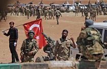  رجل يحمل العلم الوطني التركي بينما يتجمع المقاتلون السوريون المدعومون من تركيا على الخطوط الأمامية مقابل القوات الكردية بالقرب من دادات في محافظة حلب شمال سوريا، 5 يوليو 2022
