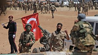  رجل يحمل العلم الوطني التركي بينما يتجمع المقاتلون السوريون المدعومون من تركيا على الخطوط الأمامية مقابل القوات الكردية بالقرب من دادات في محافظة حلب شمال سوريا، 5 يوليو 2022