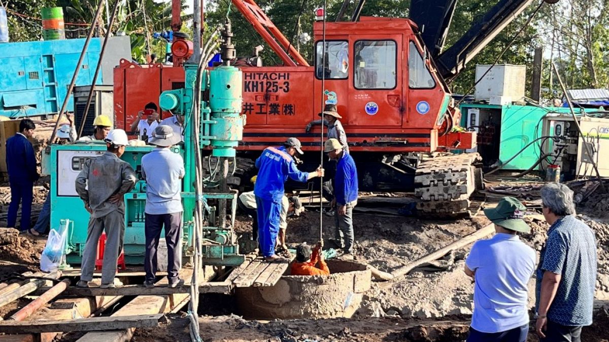  عمال الإنقاذ يعملون على رفع عمود خرساني أجوف، حيث حوصر صبي، في منطقة بناء جسر في مقاطعة دونغ ثاب الفيتنامية.