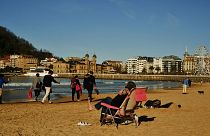 Personas tomando el sol en la playa en la ciudad española de San Sebastián