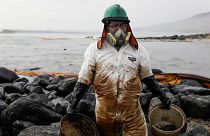 A worker cleans up an oil spill at the beach after the oil spill that has caused an ecological disaster.