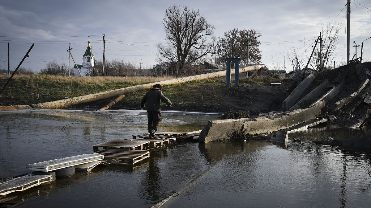 رجل يعبر النهر على حطام جسر مدمر في باخموت، موقع أعنف المعارك مع القوات الروسية في منطقة دونيتسك، أوكرانيا. 2022/12/11