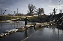 رجل يعبر النهر على حطام جسر مدمر في باخموت، موقع أعنف المعارك مع القوات الروسية في منطقة دونيتسك، أوكرانيا. 2022/12/11