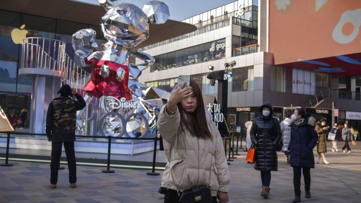 Nő készít szelfit magáról egy pekingi bevásárlóközpont előtt 2023. január 5-én