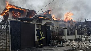 Tűzoltó egy orosz bombázás után égő háznál Herszonban