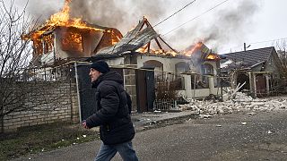 A local resident runs past a burning house hit by the Russian shelling in Kherson on 6 January 2023