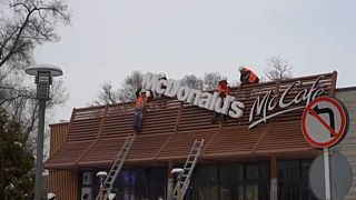 Workers take down a McDonald's sign from a restaurant in Almaty, Kazakhstan