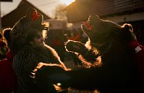 People wearing bear fur costumes prepare to take part in a parade showcasing regional winter traditions in Comanesti, northeastern Romania, Friday, Dec. 30, 2022.