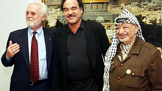 صورة من الارشيف- الزعيم الفلسطيني الراحل ياسر عرفات مع الكاتب الأمريكي راسل بانكس (يسار) والمخرج السينمائي أوليفر ستون (وسط)- رام الله بالضفة الغربية- 25 مارس 2002