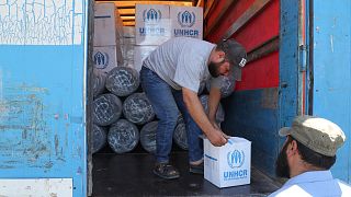 عمال يفرغون شاحنة مساعدات تابعة للأمم المتحدة في سوريا.
