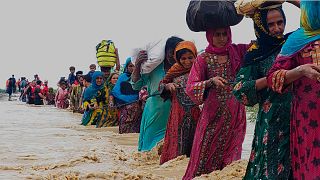 Rescue workers help residents evacuate from a flooded area caused by heavy rains, in Lasbella, Pakistan, July 2022.