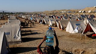 A displaced girl carries a bottle of water she filled from nearby stranded flood-waters, as her family takes refuge in a camp, in Sehwan, Pakistan, September 30, 2022. 