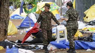 Des soldats aident à nettoyer un campement installé par des partisans de l'ancien président brésilien Jair Bolsonaro devant le quartier général de l'armée à Brasilia