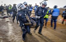 Rendőrök visznek egy tüntetőt, hogy megtisztítsanak egy utat a németországi Erkelenz közelében lévő Luetzerath településen 2023. január 10-én