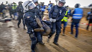 Rendőrök visznek egy tüntetőt, hogy megtisztítsanak egy utat a németországi Erkelenz közelében lévő Luetzerath településen 2023. január 10-én