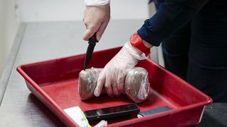 Полицейский открывает упаковку с конфискованным с парижском аэропорту кокаином. Архив
