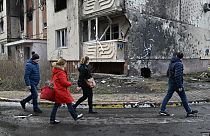 People walk past a Banksy’s graffiti on a wall of a heavily damaged residential building in Irpin, Kyiv, on December 23, 2022, amid the Russian invasion of Ukraine