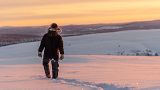 Um pastor de renas da comunidade de Laevas Sami caminha na neve enquanto o sol se põe na montanha Longastunturi perto de Kiruna, Suécia.