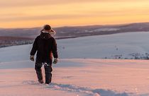  Um pastor de renas da comunidade de Laevas Sami caminha na neve enquanto o sol se põe na montanha Longastunturi perto de Kiruna, Suécia.