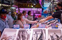 یک مشتری در بازار ماراویلاس در مادرید در حال پرداخت هزینه ماهی است که خرده است، ۱۲ می ۲۰۲۲