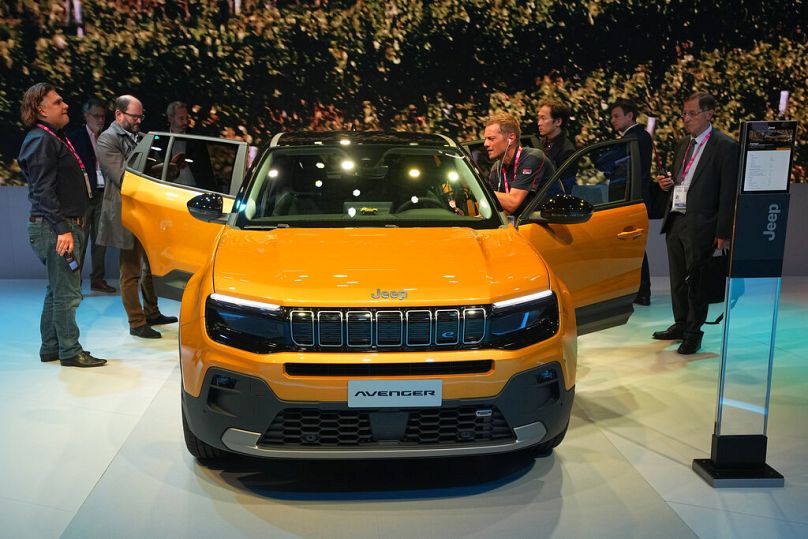 People gather around the electric-powered Jeep Avenger SUV at the Paris Car Show Monday, Oct. 17, 2022 in Paris.